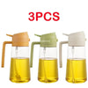 Three clear glass oil spray bottles with light yellow oil and white/green pump tops.