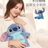A woman is holding a blue cartoon plush toy, which is a hot water bottle, in a cozy indoor setting.