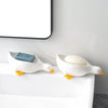 A white ceramic duck shaped soap dish with an orange beak sits on a white bathroom counter.
