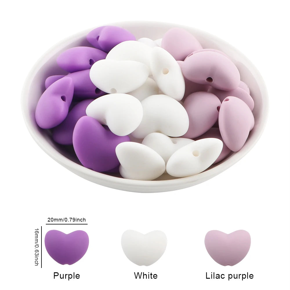 A bowl filled with 10 silicone heart-shaped charm beads in purple, white, and lilac purple colors.