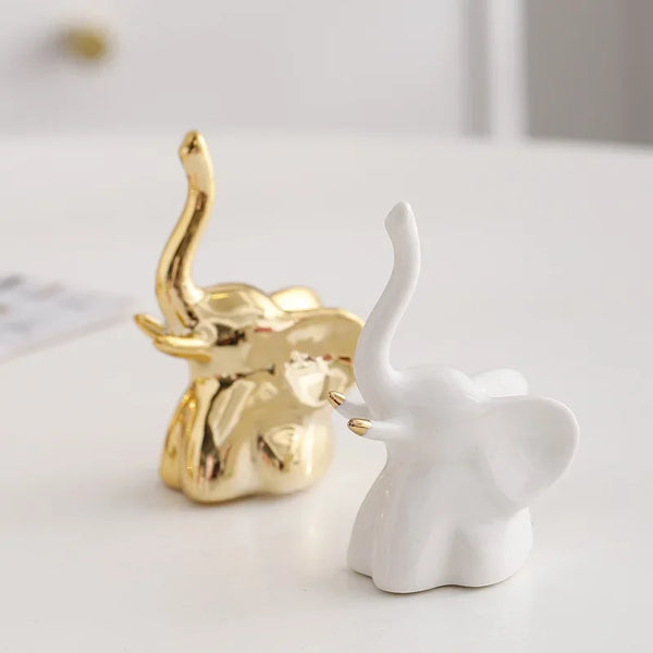 A pair of ceramic elephant rabbit jewelry racks, one gold and one white, displayed on a white surface.