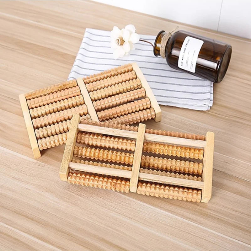 Ein Set aus Holz-Fußmassiererollern und eine Glasflasche werden auf einer hellen Holzoberfläche präsentiert.