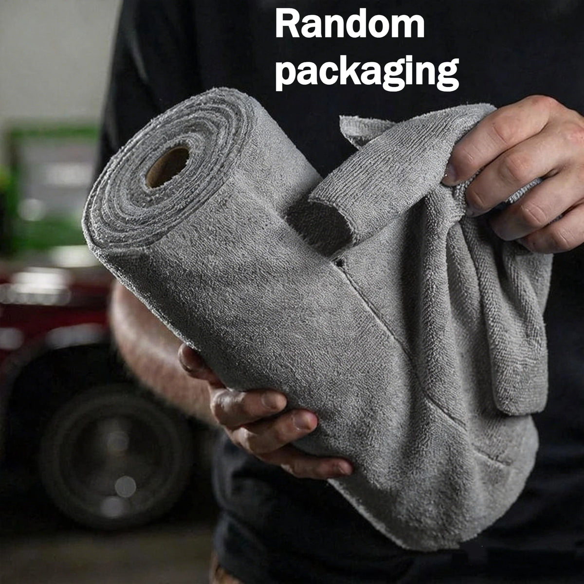 A hand holds a roll of gray tearable microfiber cleaning wipes.