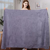 A woman holds up a large, soft gray ultra-absorbent microfiber bath towel against a light background.