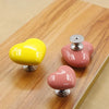 A set of heart-shaped toilet presser buttons in yellow and pink resting on a wooden surface.
