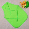 A bright lime green non-woven craft apron folded and displayed on a beige fabric with orange flowers.