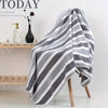 A gray and white striped bath towel draped over a wooden hanger against a white background.