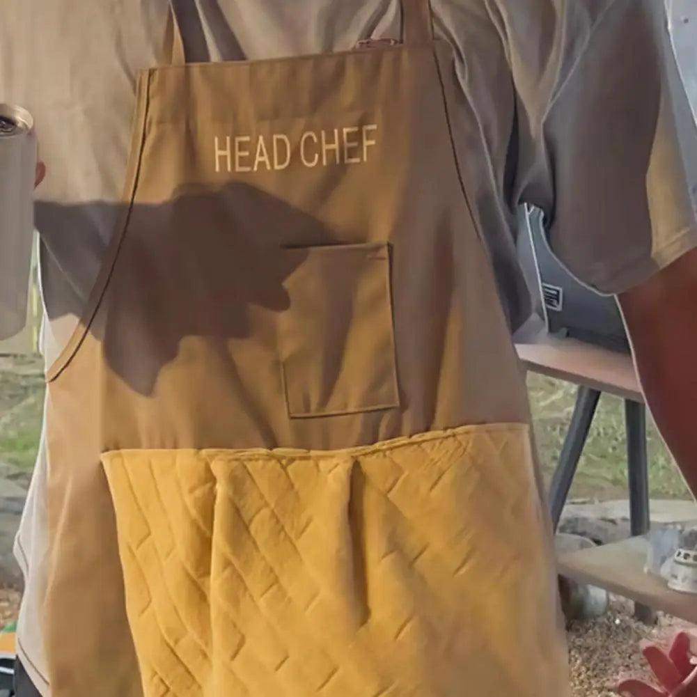 A beige chef apron with the text HEAD CHEF and a yellow quilted pocket on a person's torso.