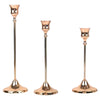 A set of three elegant rose gold metal candle holders with slender stems and flared bases.