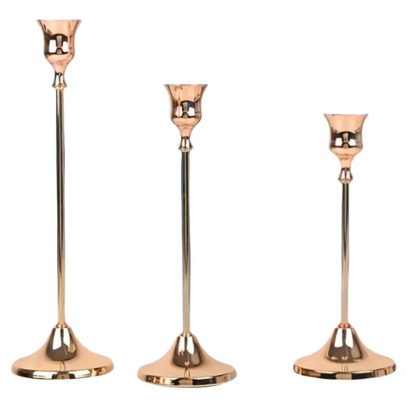 A set of three elegant rose gold metal candle holders with slender stems and flared bases.