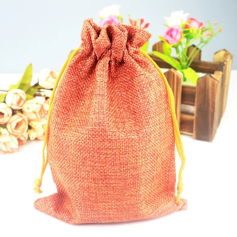 Rust-orange handgemachte Jute- und Leinen-Geschenktasche mit rosa-weißen Blumen im Hintergrund