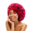 A woman wearing a vibrant red satin sleeping cap tied in a bow.