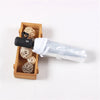 A black automatic transparent folding umbrella is shown next to a wooden box filled with natural straw balls.
