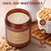 A jar of coffee scented soy wax candle next to loose coffee beans and a white ceramic pitcher.