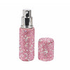 A silver perfume spray bottle with a pink glittery glass body and a matching round container.