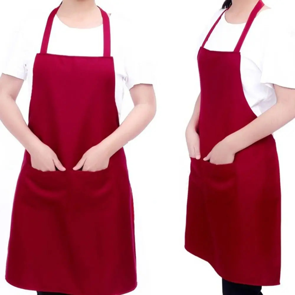 A deep red oil-proof cooking apron worn over a white shirt, featuring pockets.