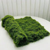 A vibrant green artificial moss garland spread out on a white surface.