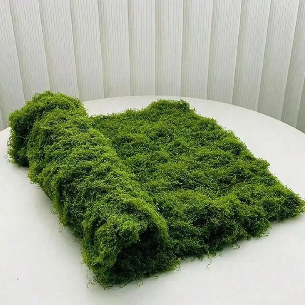 A vibrant green artificial moss garland spread out on a white surface.