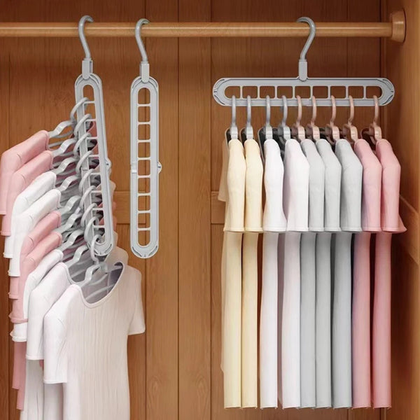 A wooden clothing rack displaying a set of light pink, white, and gray hangers.