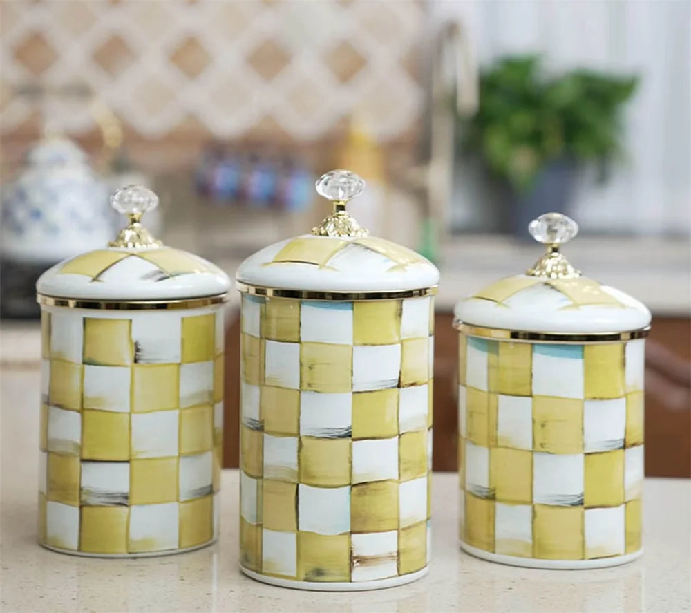 A set of three retro enamel storage jars with gold lids featuring a white and gold checkered pattern.