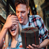 Ein junger Mann lächelt und hält eine schwarze Geschenkbox für ein DIY-Fotoalbum.
