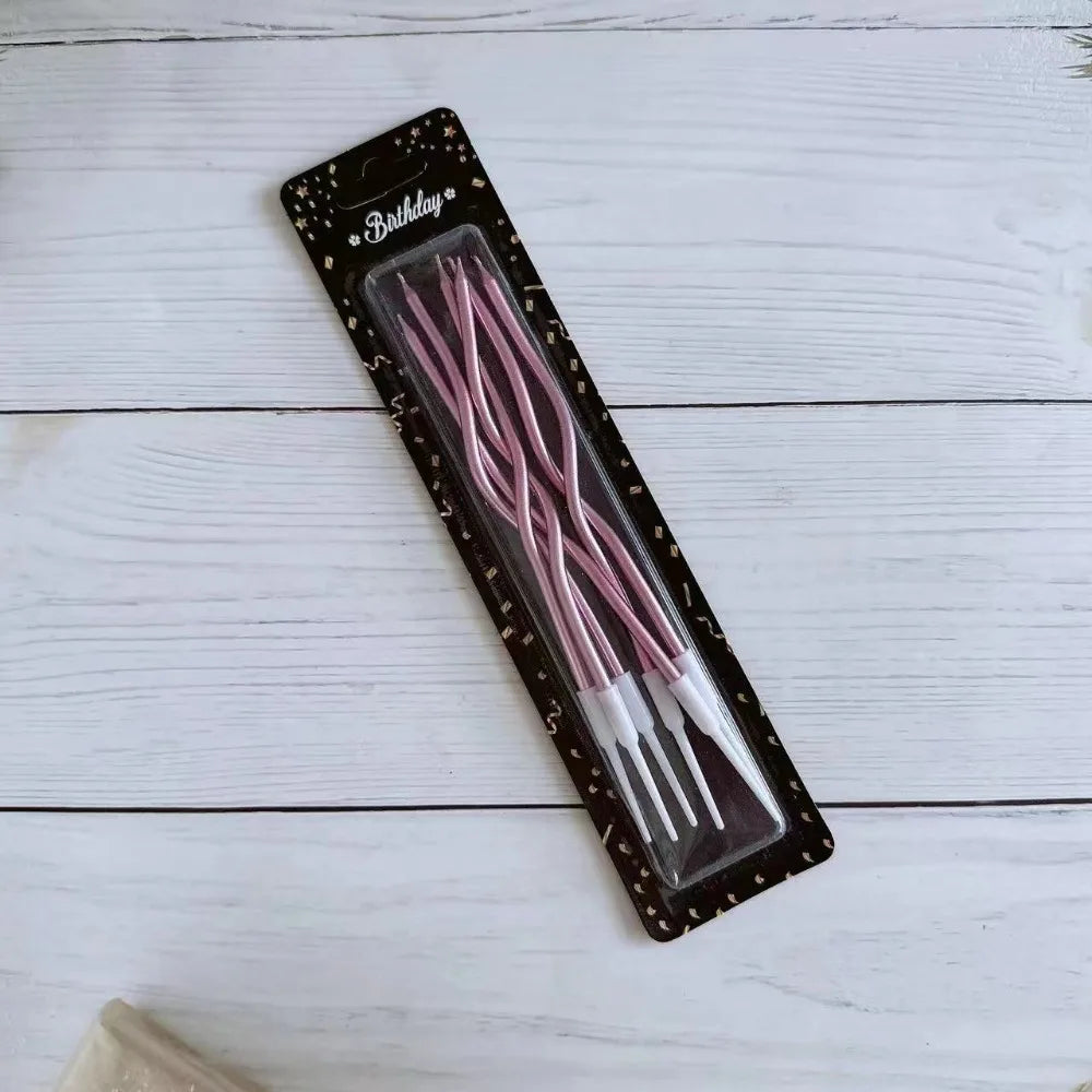 Set rosa dekorative Spiralkerzen zum Geburtstag in schwarzer Box auf weißer Holzoberfläche