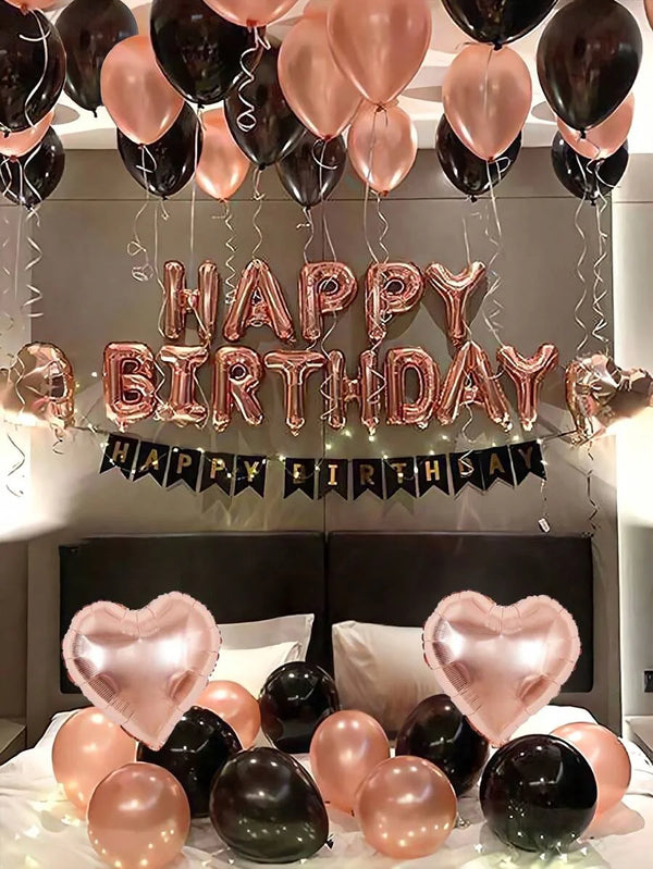 A display of rose gold and black foil balloons spelling out Happy Birthday with a banner.