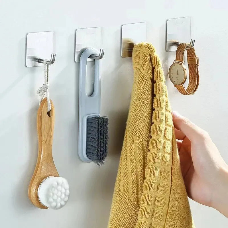 A hand is hanging a yellow textured towel on a wall using multi-use stainless steel adhesive hooks.