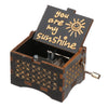 A vintage engraved wooden music box with a lid showing the text you are my sunshine.