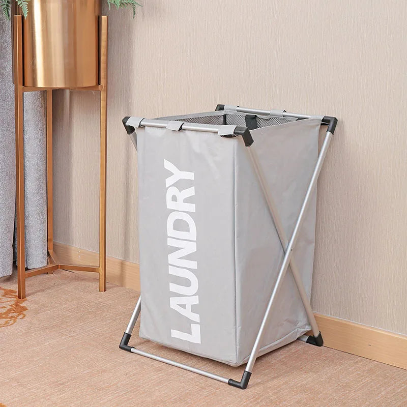 A gray foldable waterproof laundry basket with a metal frame is shown standing on a light-colored rug.