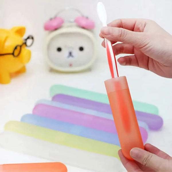 A hand holds an orange toothbrush case with multiple colored brushes and a pink toothbrush above a stack of colorful silicone
