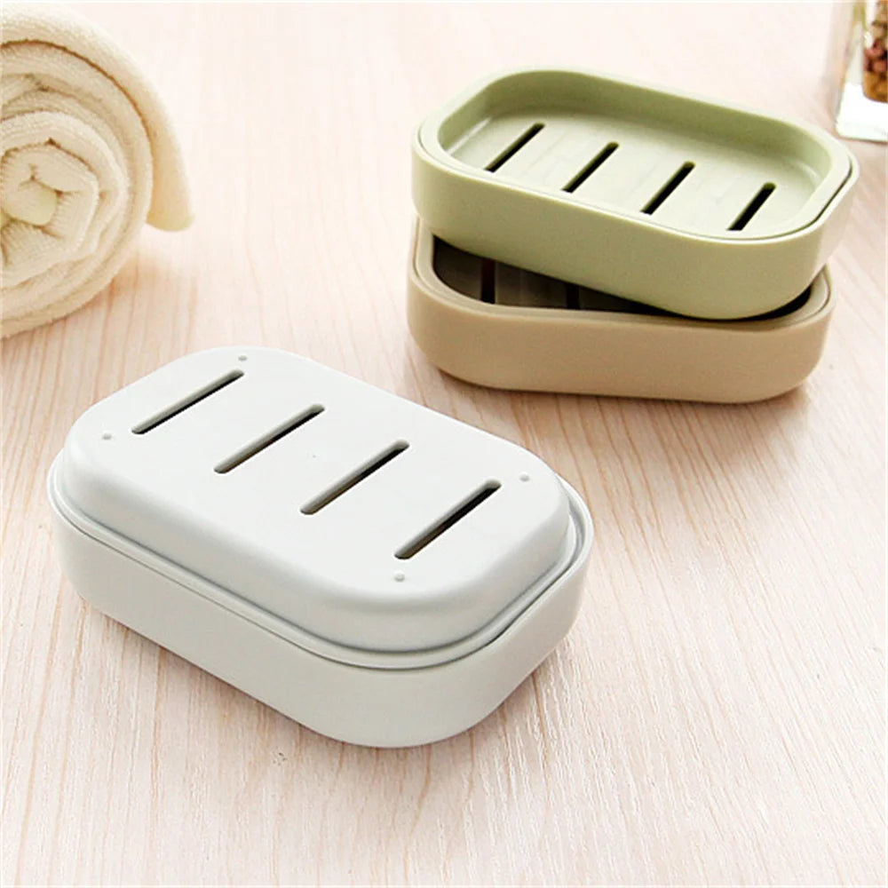 Two double layer drain soap dishes in light green and off-white colors resting on a wooden surface.