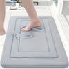A person's foot is placed on a gray non-slip absorbent bath mat for floors.
