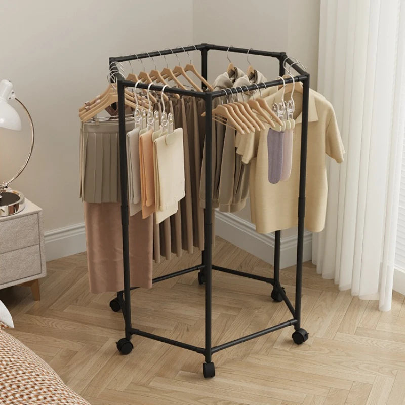 A black rotating hexagon clothes rack with wooden hangers displaying various garments in a bright room.
