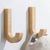 Natural oak wood wall hooks with screws mounted on a white wall.