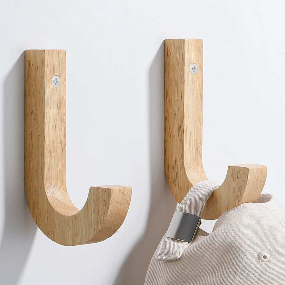 Natural oak wood wall hooks with screws mounted on a white wall.