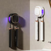 A white portable UV electric toothbrush cleaner with two brush heads hanging on a wall.