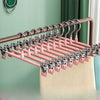 A rack of pink stainless steel adjustable clothing hangers displayed against a light green wall.