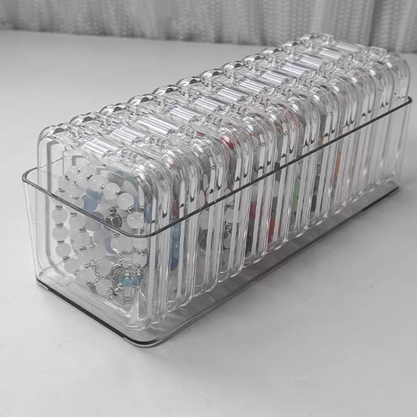 A clear plastic jewelry organizer box filled with various rings and bracelets.