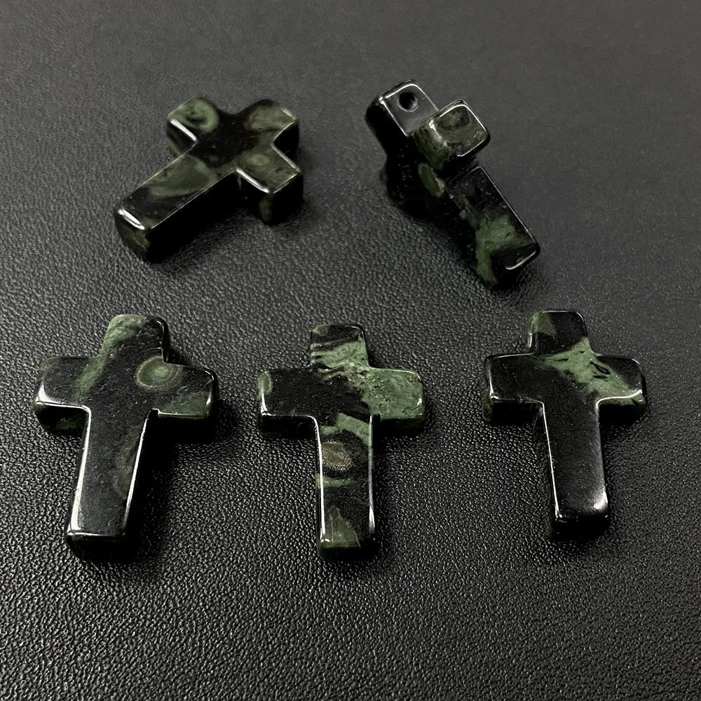 Three dark green natural agate and jasper cross pendant charms arranged on a black surface.