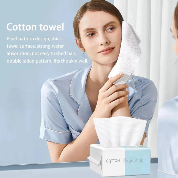 A woman is using a white cotton facial wipe on her face in a bathroom setting.