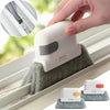 Una mano usa un cepillo de limpieza blanco para limpiar un riel de ventana, con otros cepillos visibles abajo.