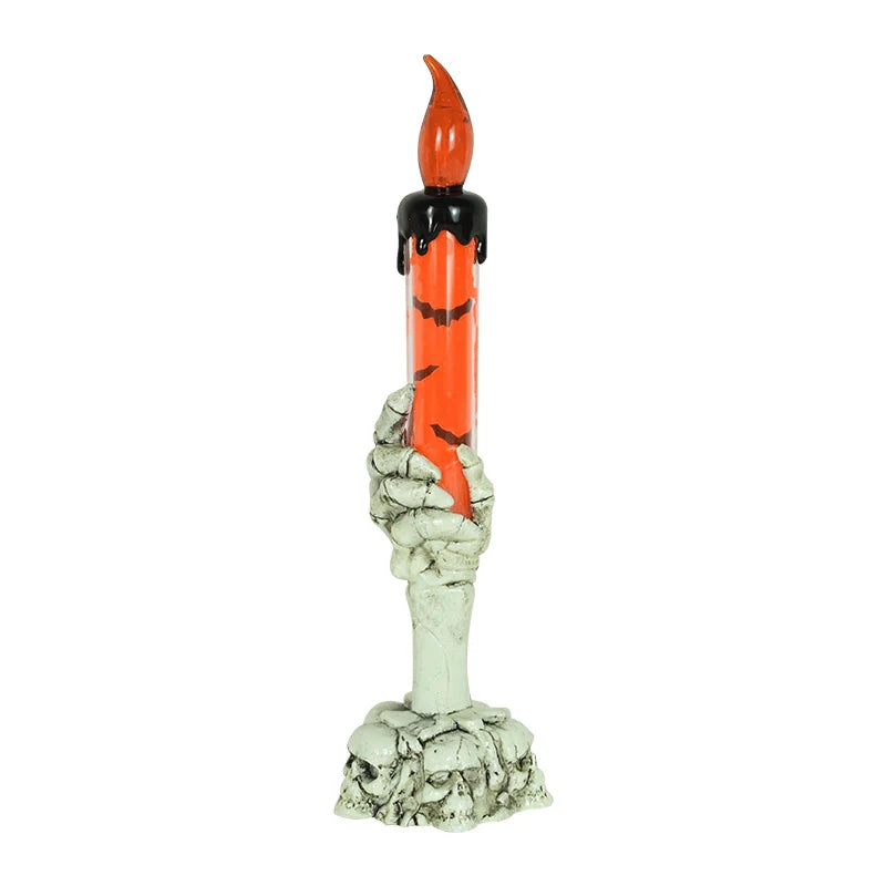 A skeleton hand sculpture holding an orange and black LED candle.