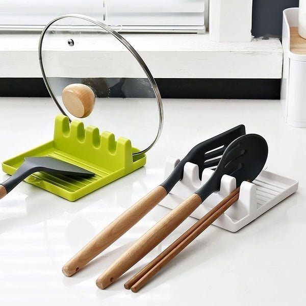 A set of black and wood kitchen utensils, including spatulas and spoons, are displayed on a white tray next to a clear magnif