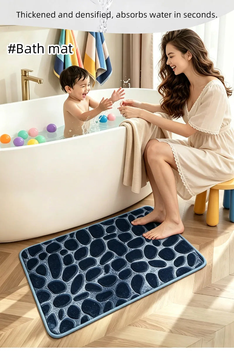 A woman is sitting by a bathtub with a child, and a dark blue pebble embossed bath mat is placed on the floor.
