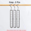 Three grey space-saving clothes organizer hangers hanging from a wooden rod.