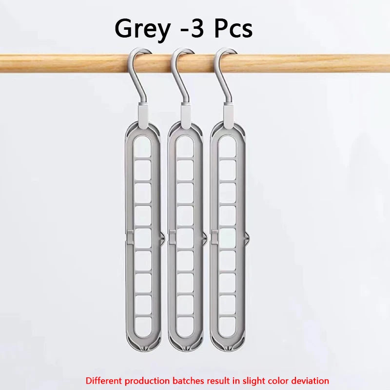 Three grey space-saving clothes organizer hangers hanging from a wooden rod.