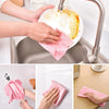 Hands are using pink reusable microfiber cleaning cloths to wash dishes in a kitchen sink.