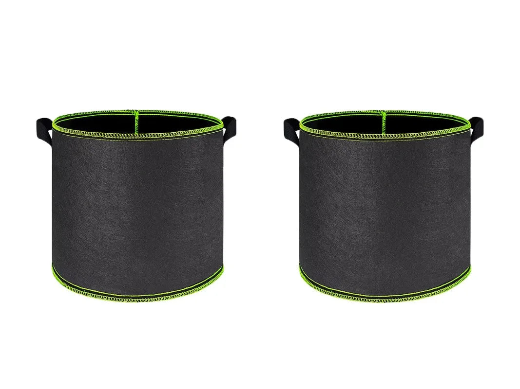 A pair of black breathable fabric plant grow bags with green trim and handles.