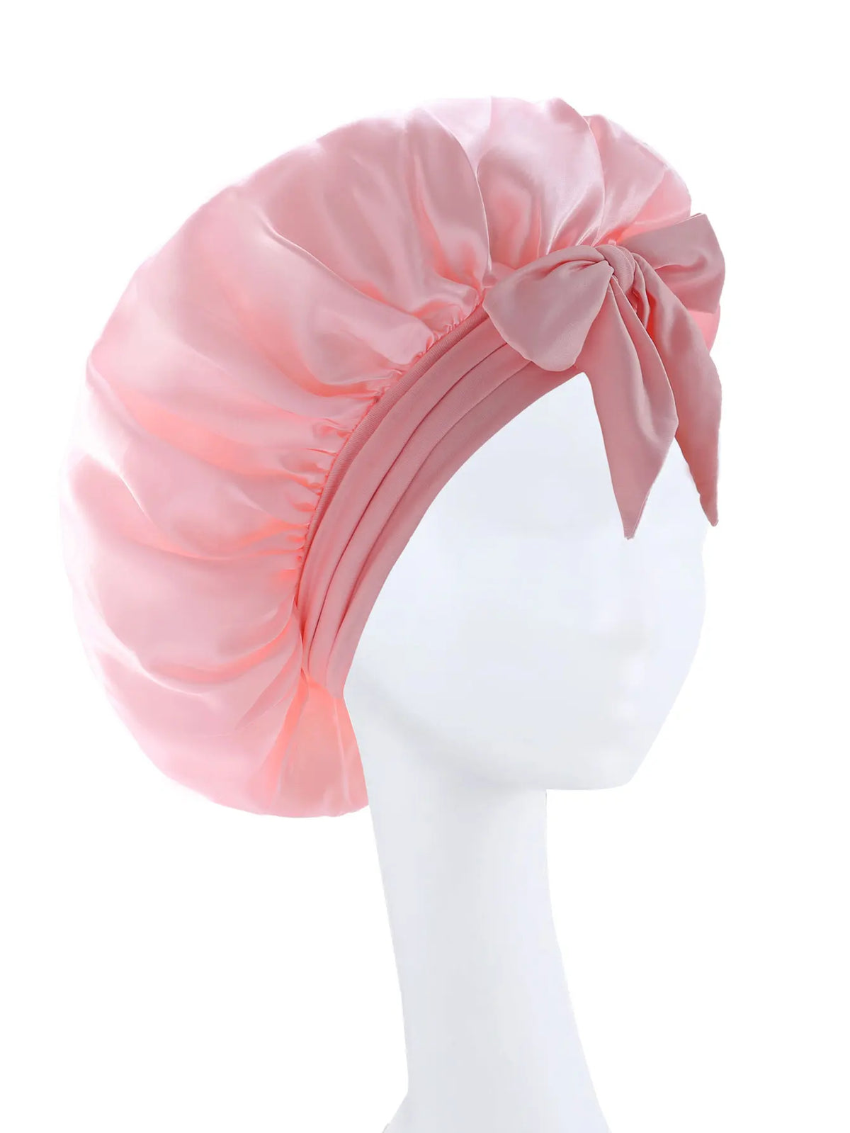 Pink silky satin sleep bonnet tied with a bow displayed on a white mannequin head.